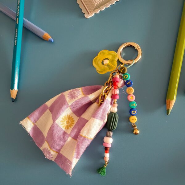 Bijou de sac fantaisie coloré avec breloques, perles multicolores et tissu vichy violet à fleurs jaunes
