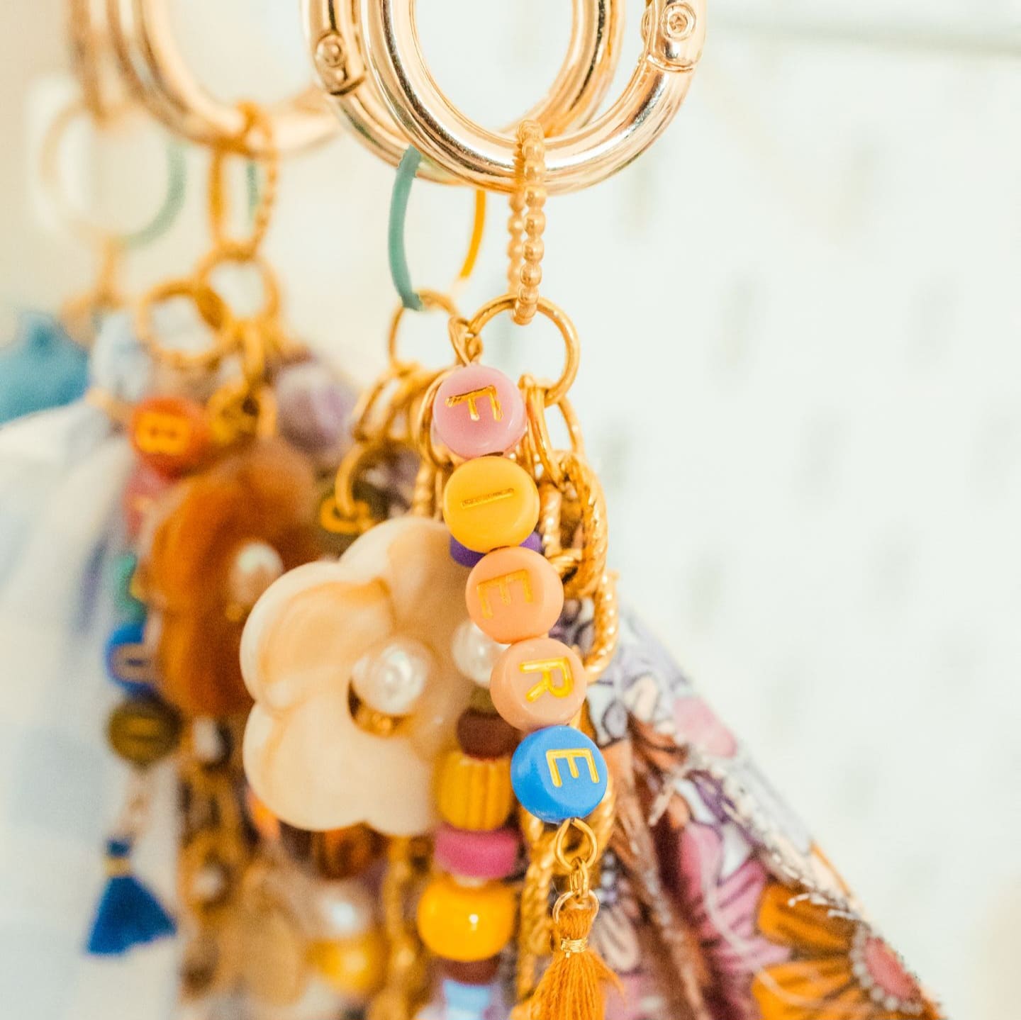 Bijou de sac coloré avec perles et message FIERE Bijou de sac fantaisie coloré, grigri porte-bonheur en perles et ruban, fait main avec message FIÈRE