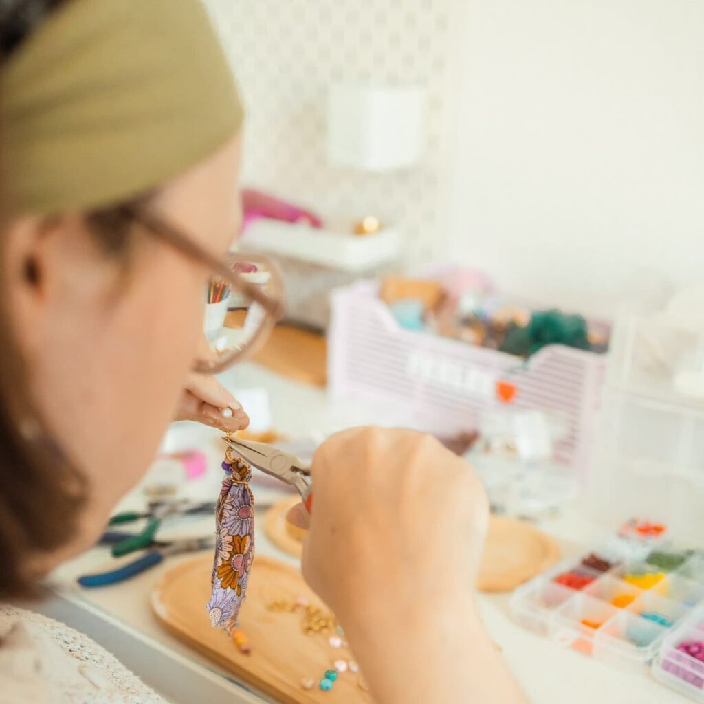 créatrice fabriquant un bijou coloré fait main avec des perles