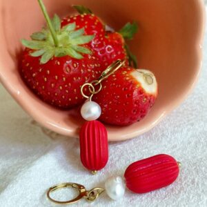 Boucles d’oreilles rouges et perle blanche photographiées avec des fraises